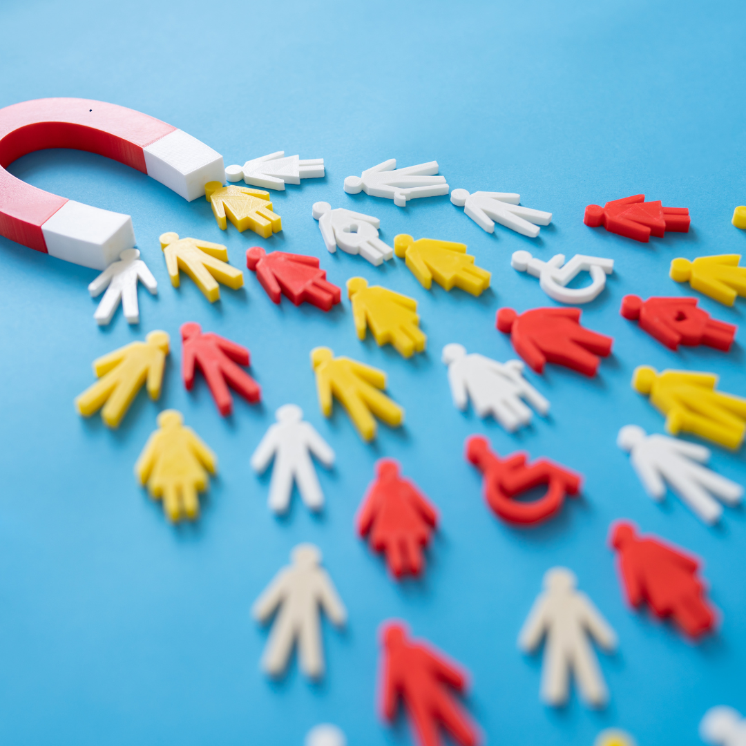 A red and white magnet is surrounded by small plastic people on a blue surface.