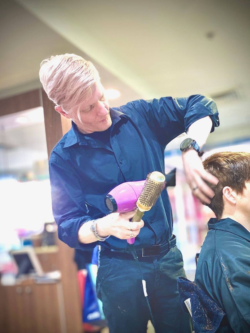 A Man is Blow Drying a Woman's Hair in a Salon — Superb Hair in Wyong, NSW