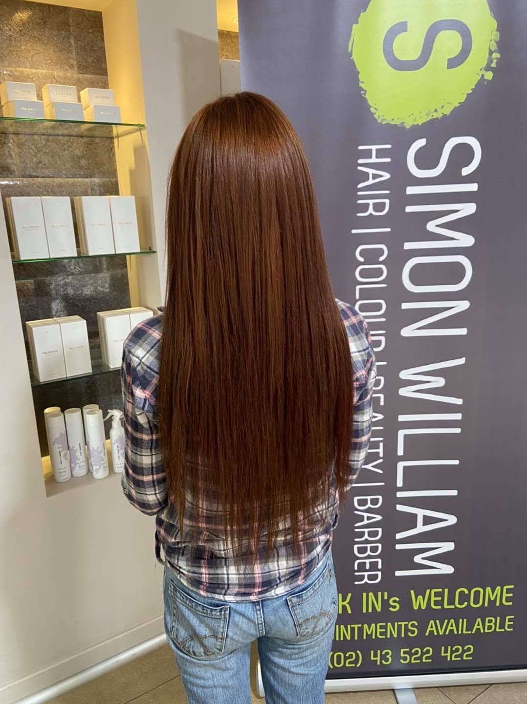 A Woman is Standing in Front of a Sign That Says Simon William — Superb Hair In Wyong, NSW