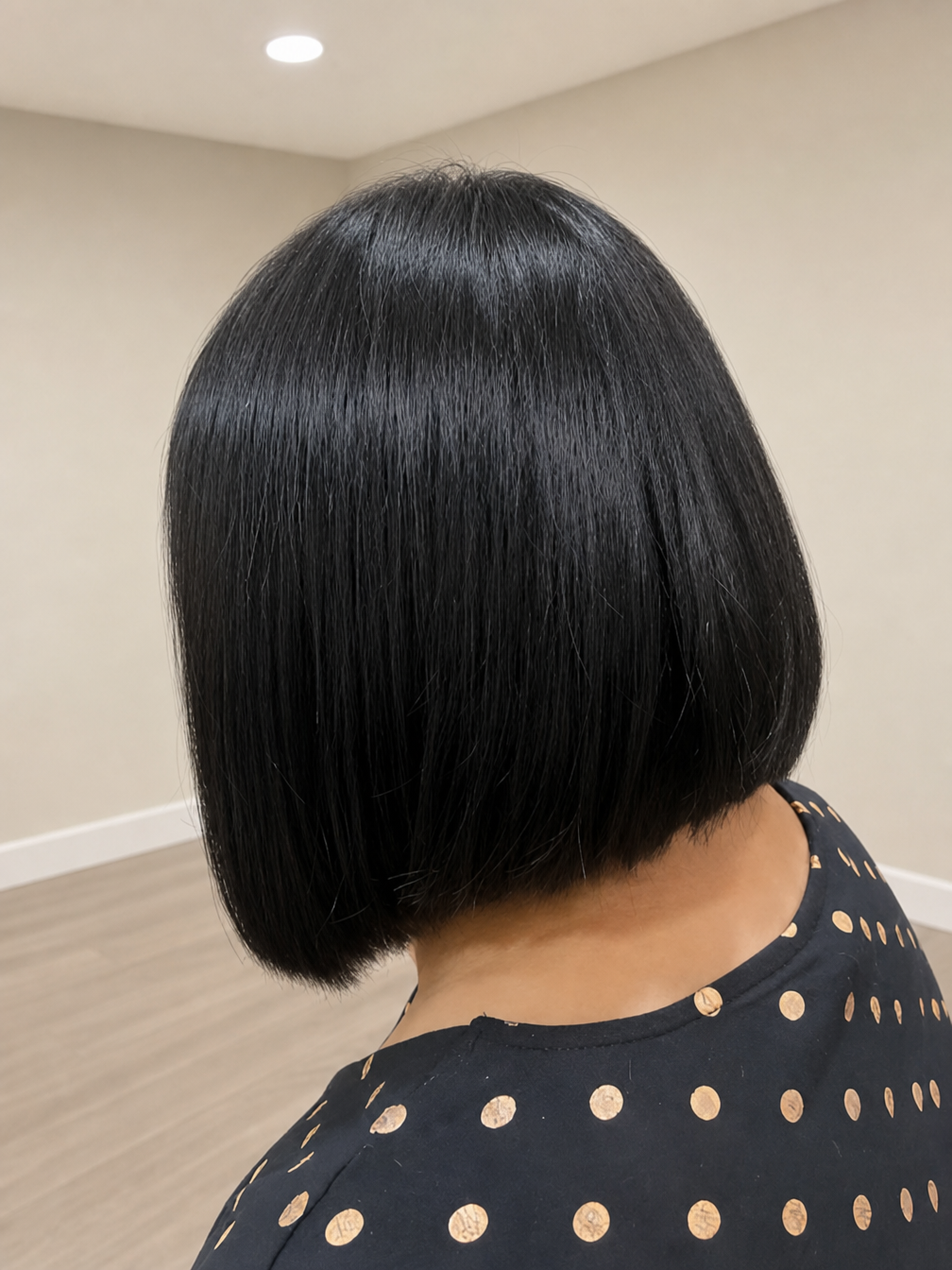 Back view of a glossy black bob haircut against a beige indoor wall — Superb Hair in Wyong, NSW