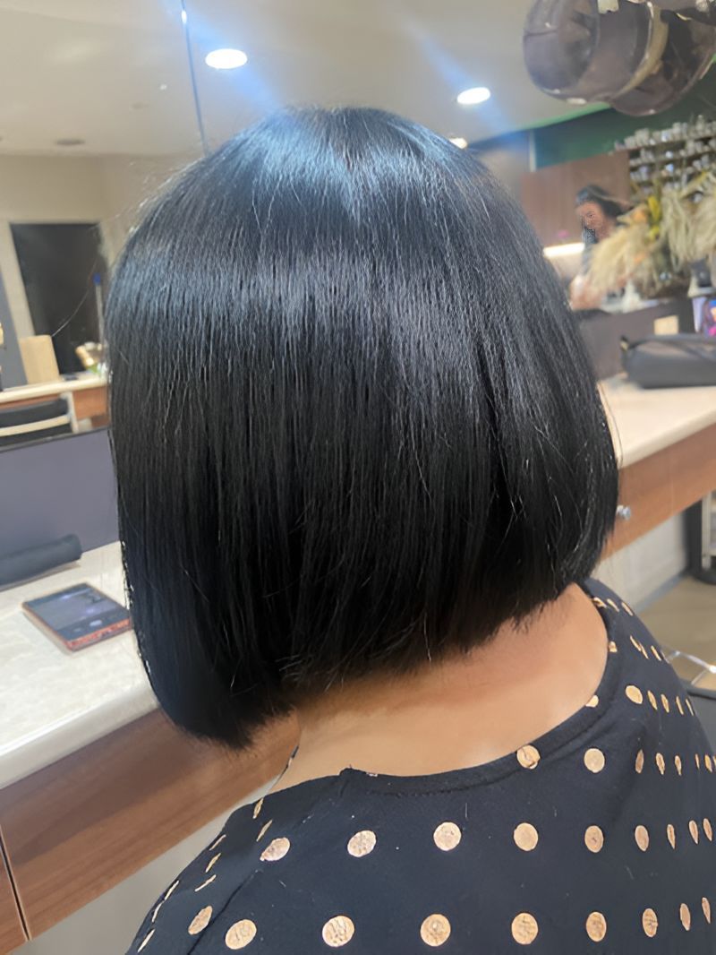 A Woman With Short Black Hair is Wearing a Polka Dot Shirt — Superb Hair in Wyong, NSW