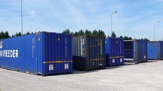 un gruppo di container blu sono parcheggiati uno accanto all'altro in un parcheggio .