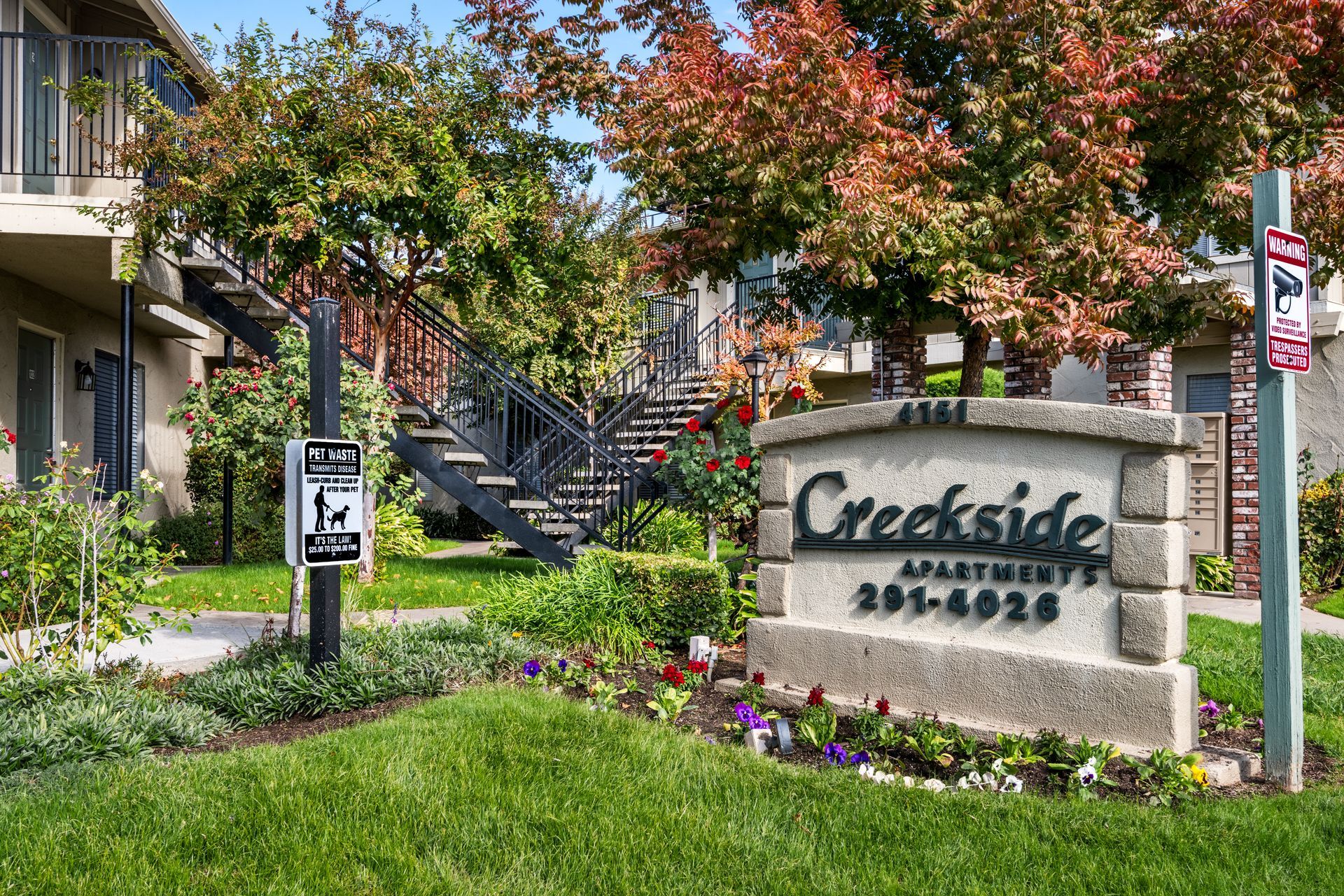 Creekside Apartments sign with landscaping, buildings, and colorful trees.