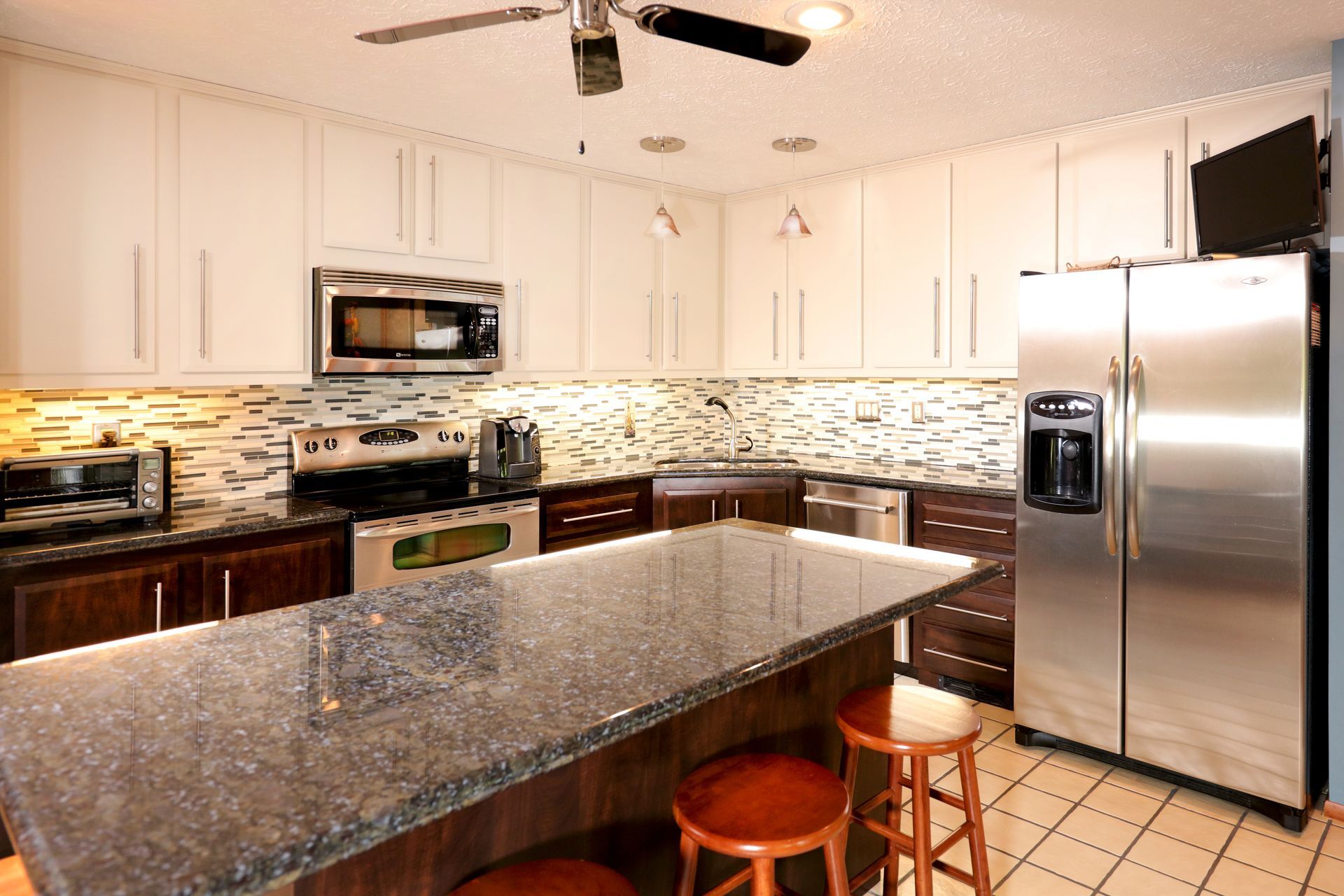 Kitchen with white upper cabinets, dark brown lower cabinets, granite countertops, and stainless steel appliances.