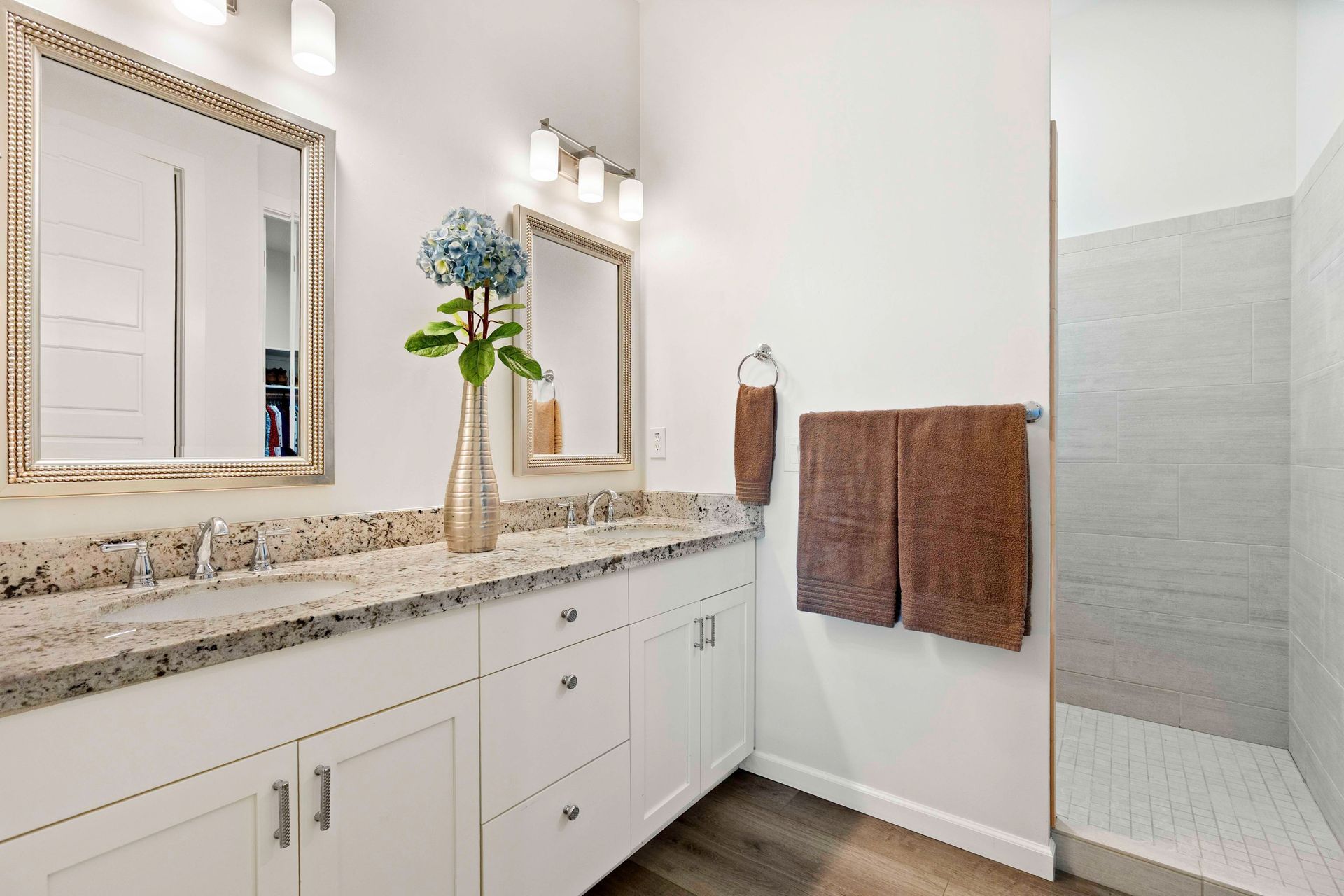 Spacious bathroom with two sinks, a large mirror, and a walk-in shower after remodeling job.