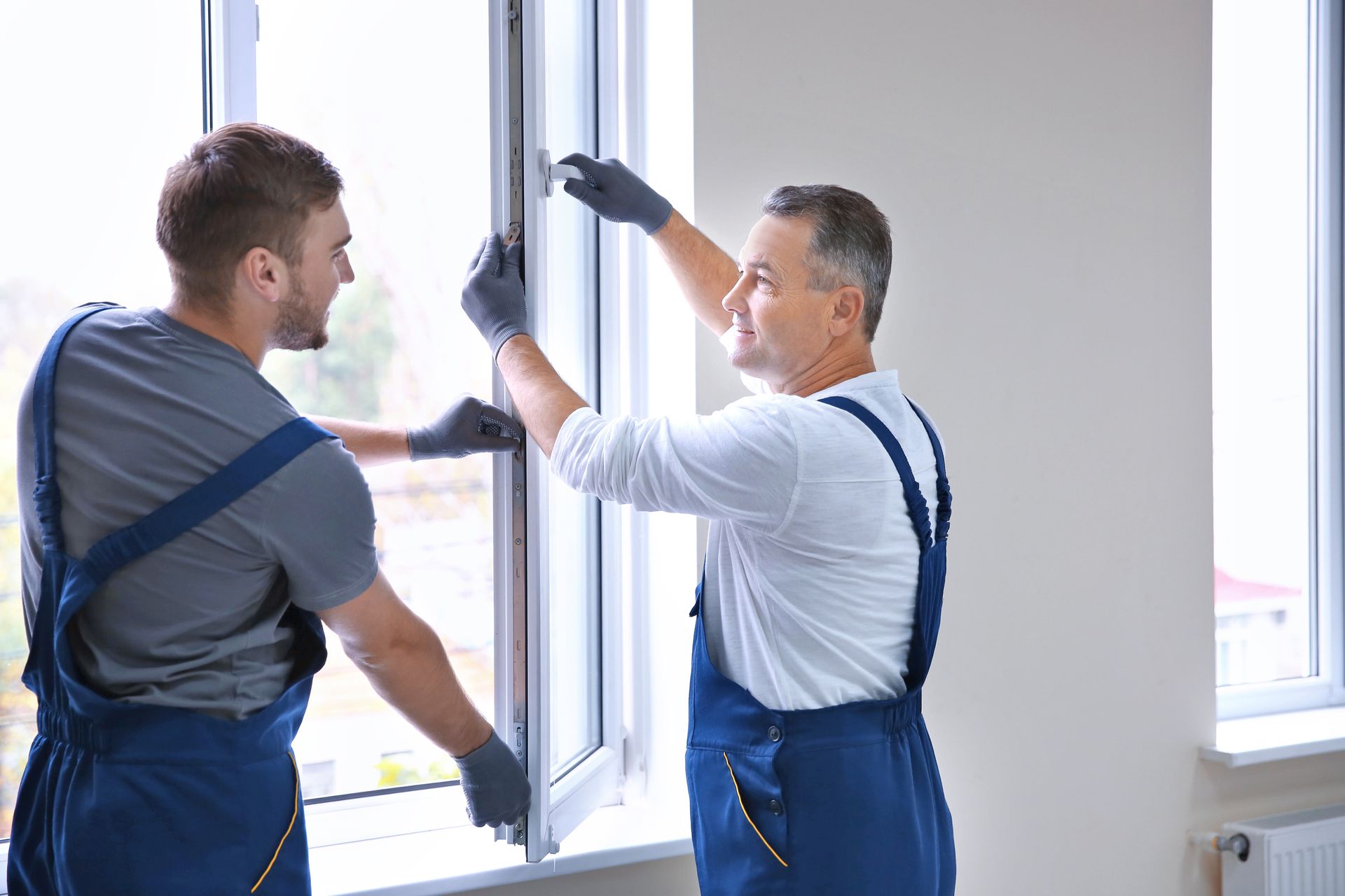 Workers from a window installation company installing a window in a house.
