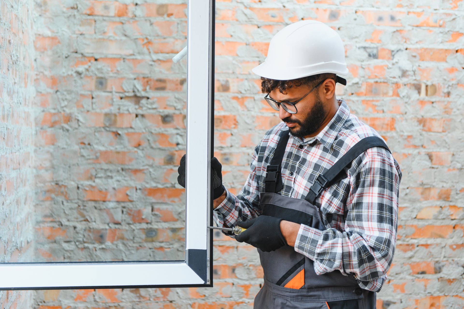 Construction worker installing window in new building.