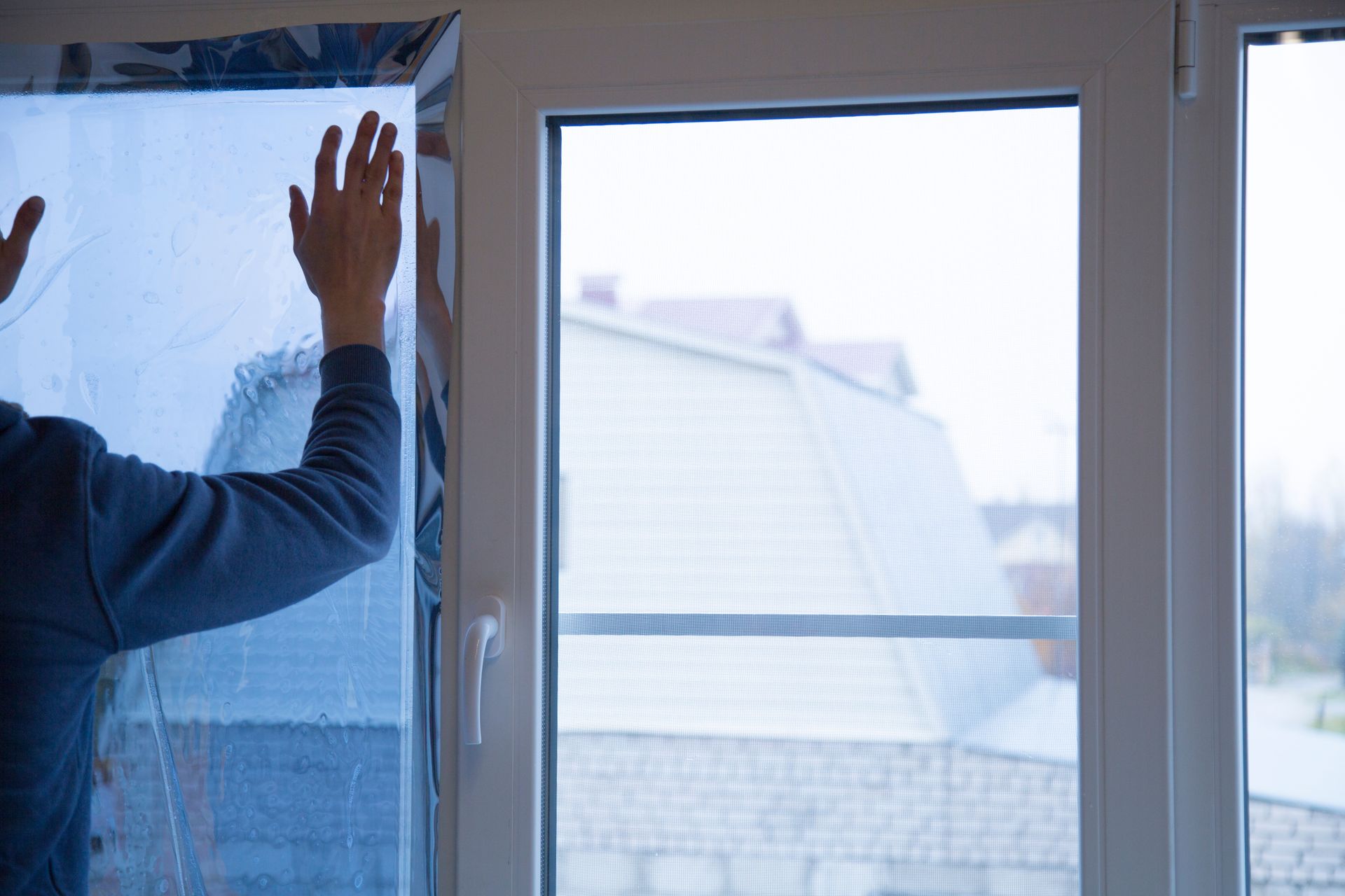 Person applying protective window film to a large glass door, smoothing the surface.