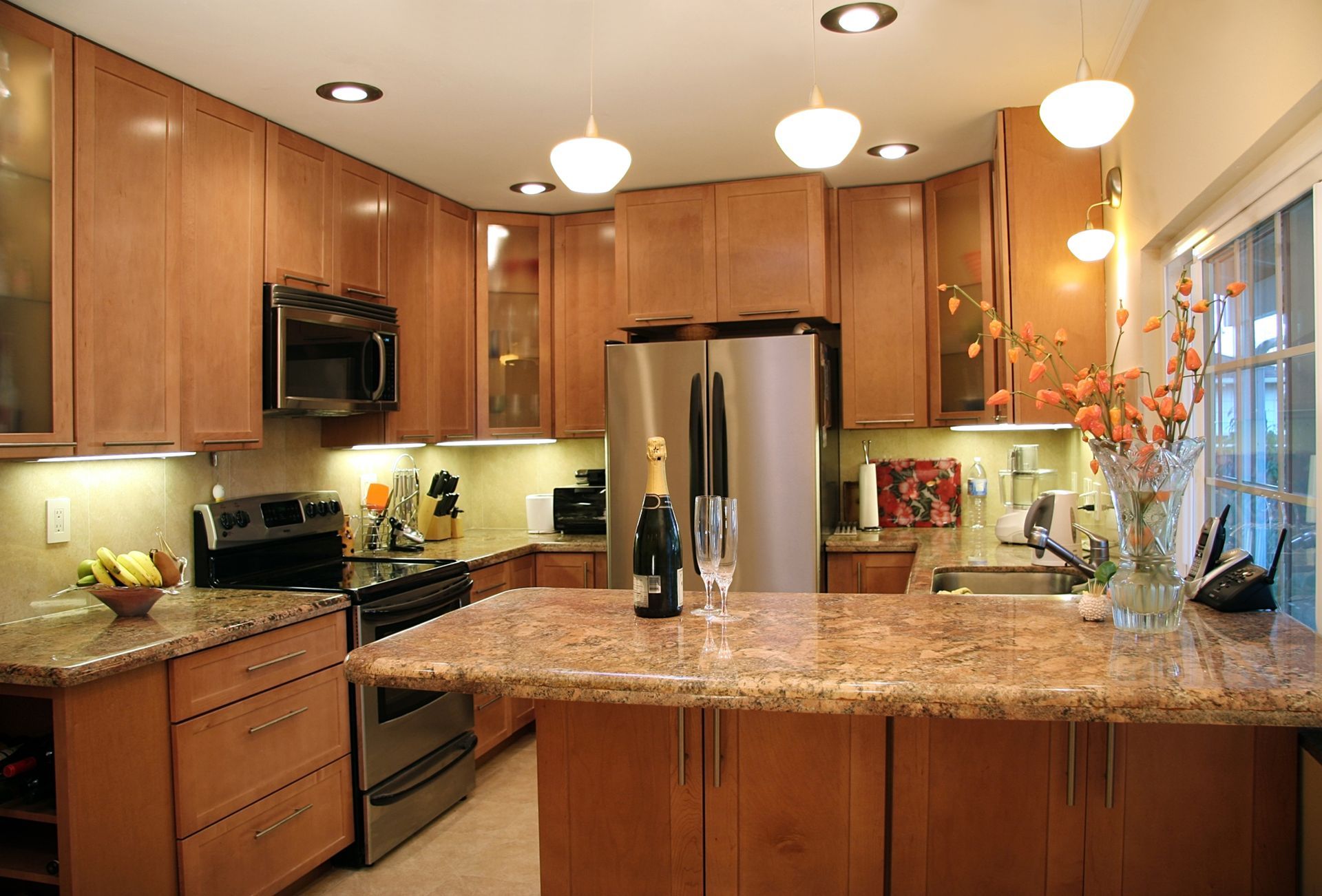 A modern kitchen with wood cabinets, granite countertops, and stainless steel appliances.