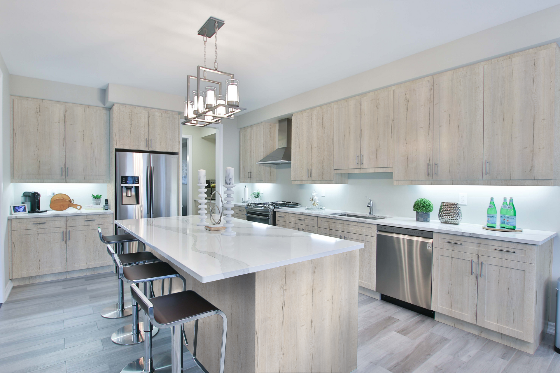 Modern kitchen with light wood cabinets, large island, and stainless steel appliances.