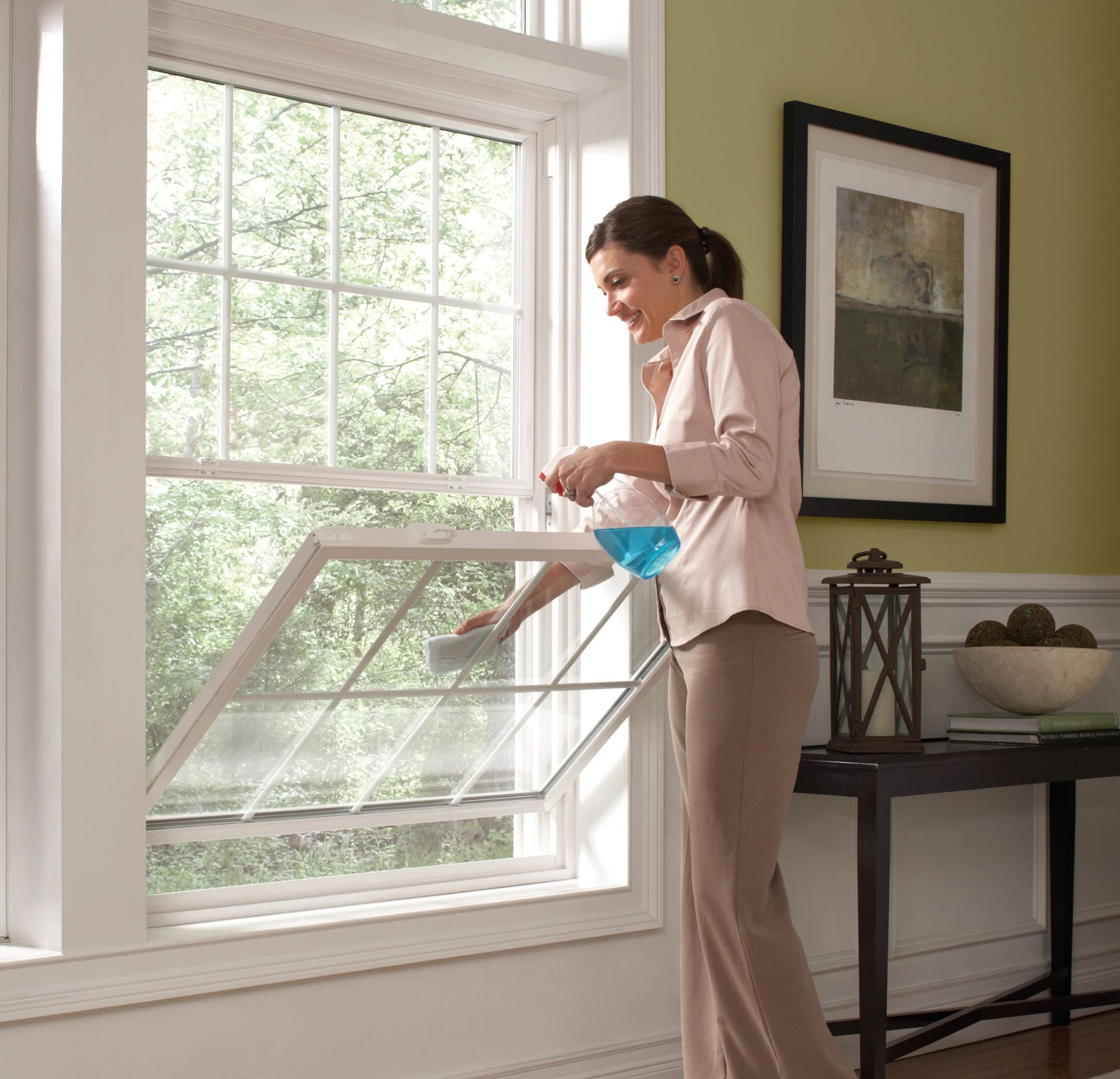 Living room with fireplace, stone surround, TV, sofa with colorful pillows, armchair, and large windows.