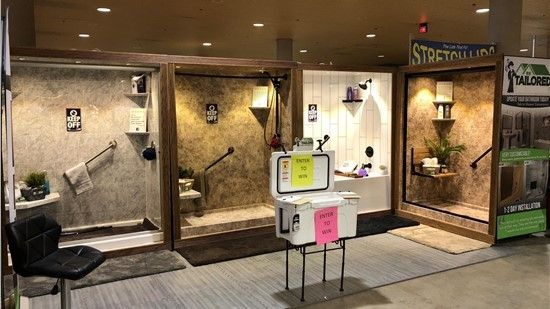 Shower stalls on display at a trade show. Each has different textured walls, features, and accessories.