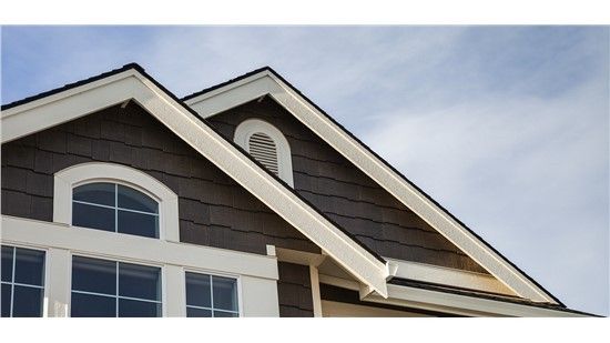 Brown house with white trim, triangular roof, and arched window.