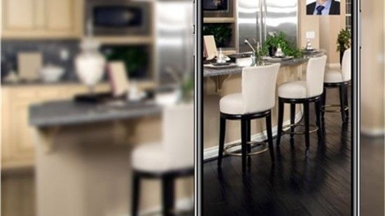 A modern kitchen with an island and bar seating. White chairs, stainless steel appliances, and dark wood floors.