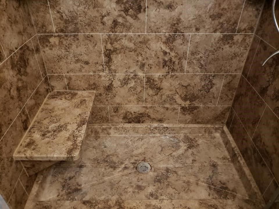 Brown tiled shower with built-in bench and drain.