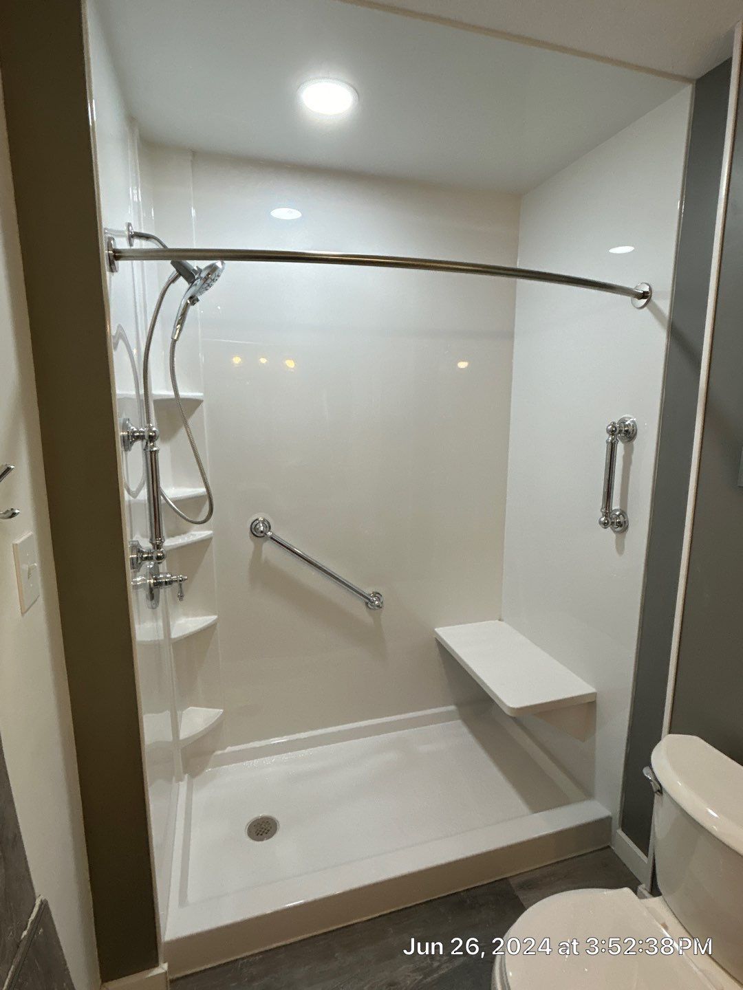 Accessible white shower with bench, grab bars, and curved shower rod.