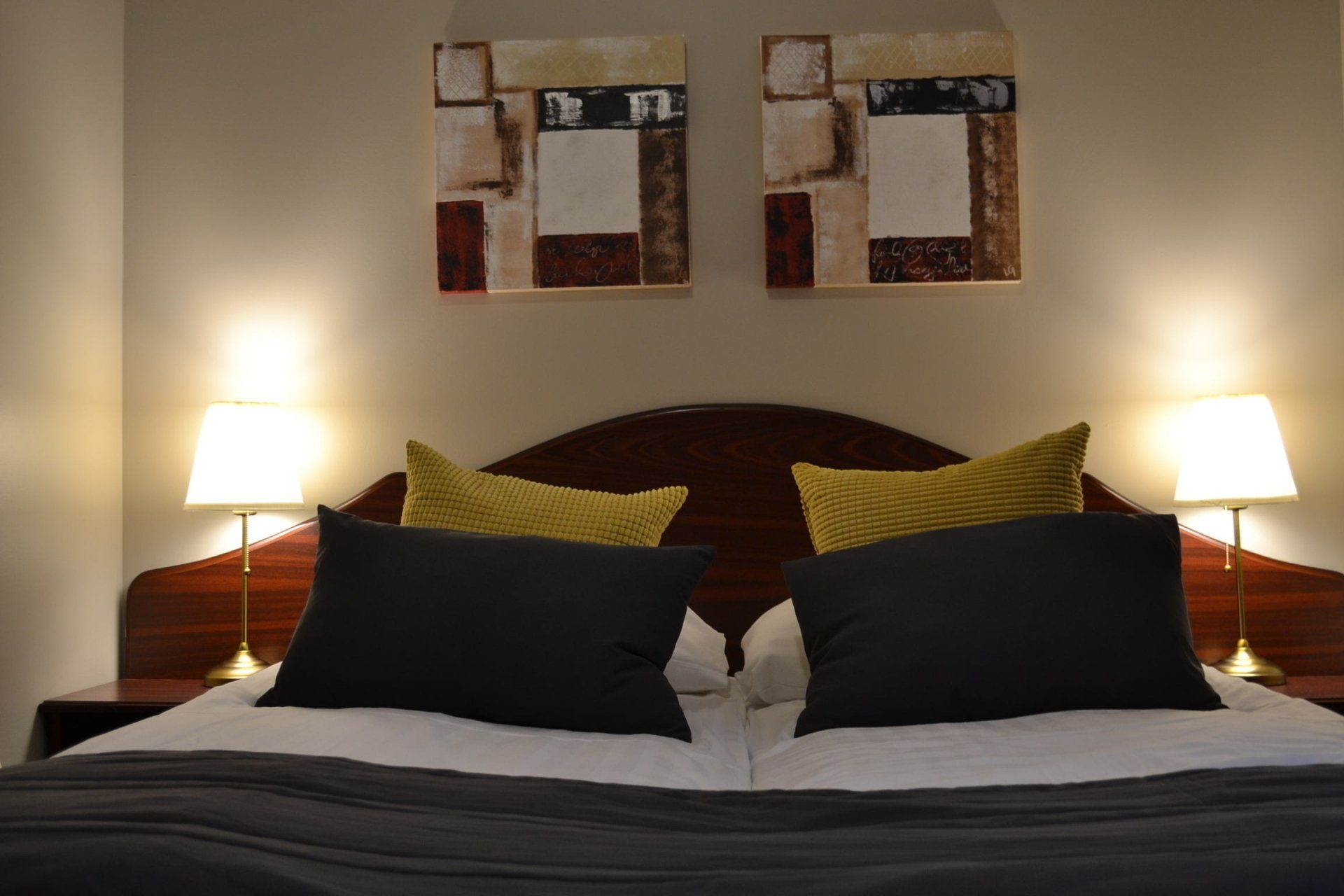 A hotel room with a bed and two paintings on the wall