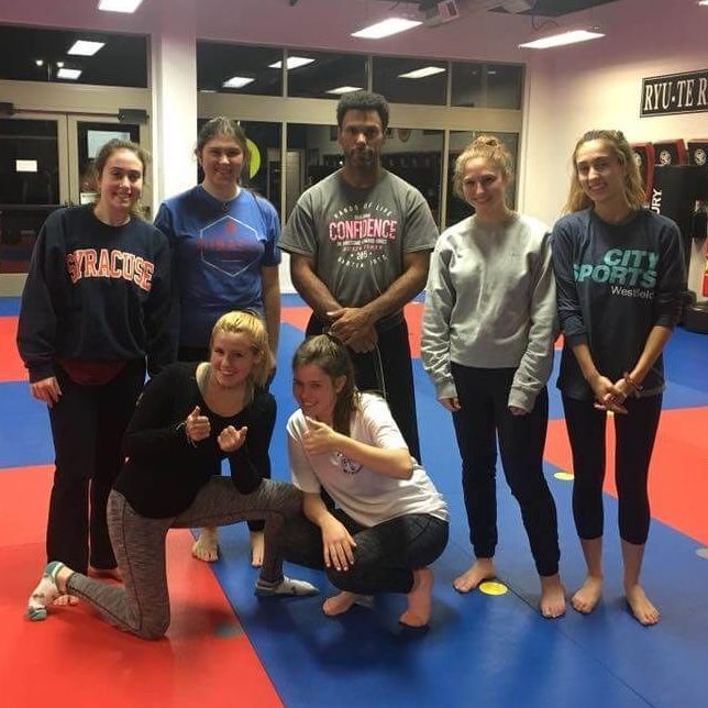 A group of people posing for a picture with one wearing a city sports sweatshirt