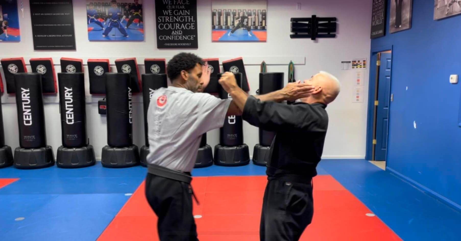 Two men are practicing martial arts in a gym.