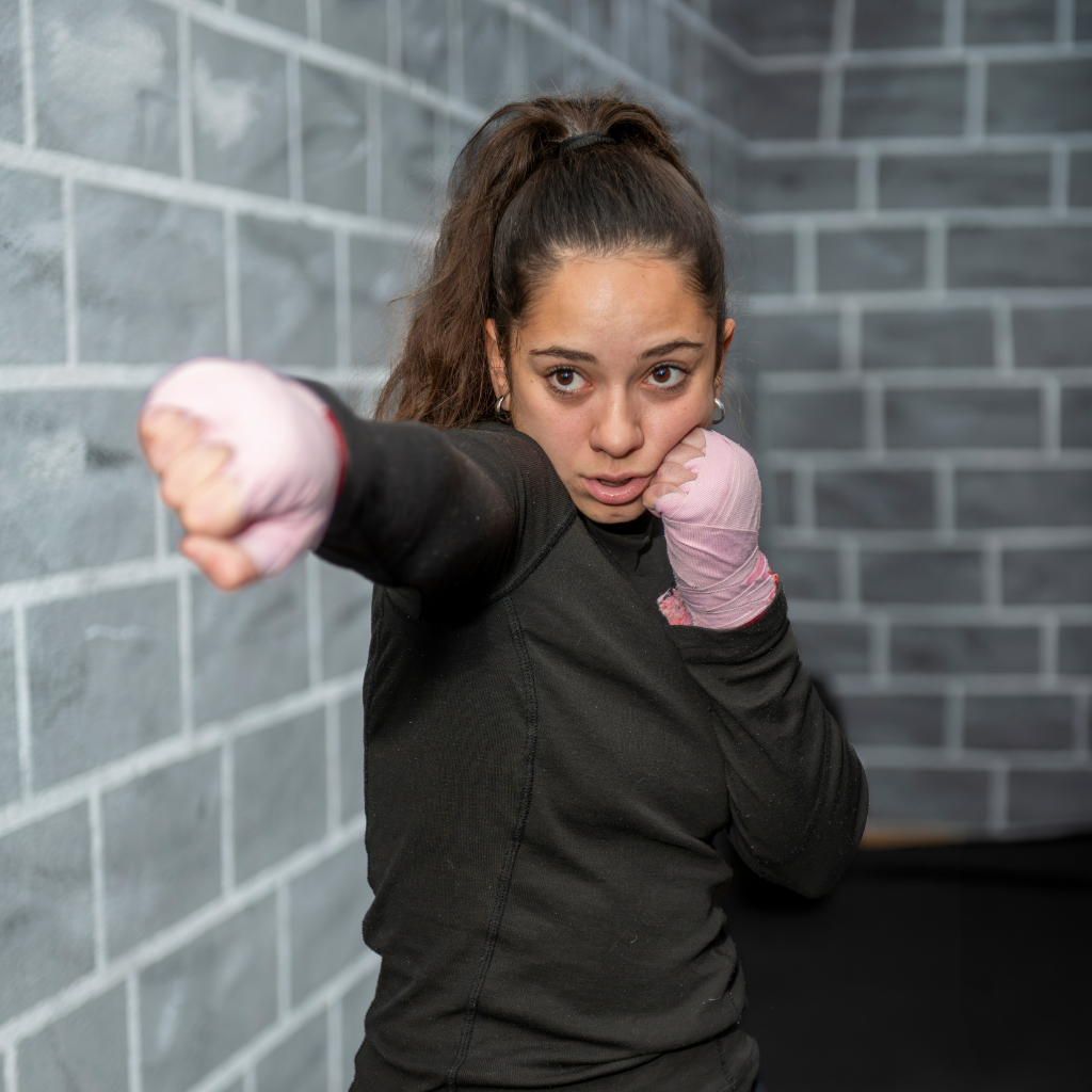 A man is kneeling down next to a young boy in a taekwondo class.