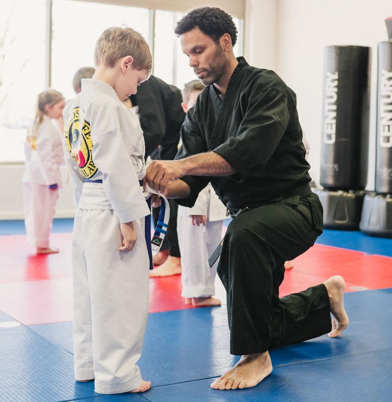 A man is helping a young boy with his karate belt