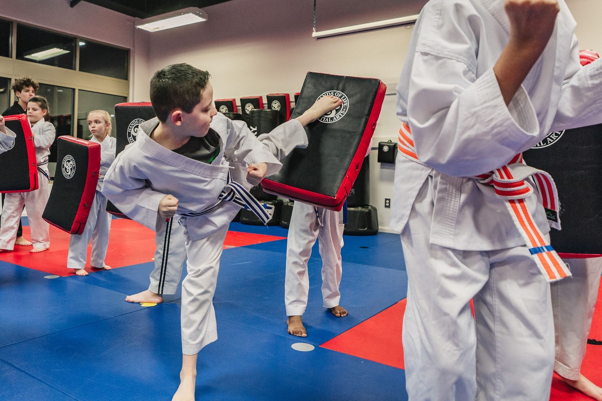 A group of young boys are practicing martial arts in a gym.