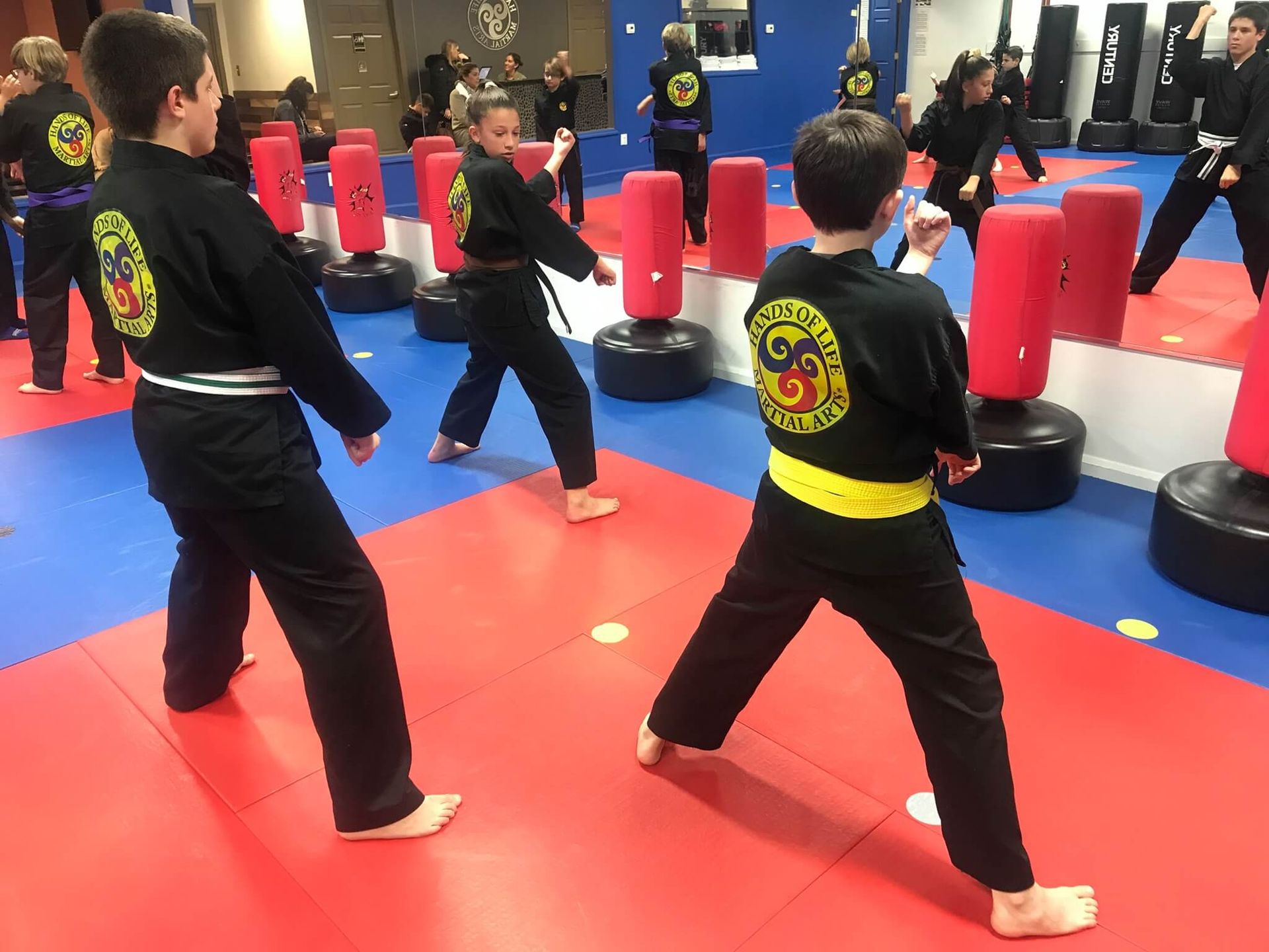 A group of children are practicing martial arts in a gym.