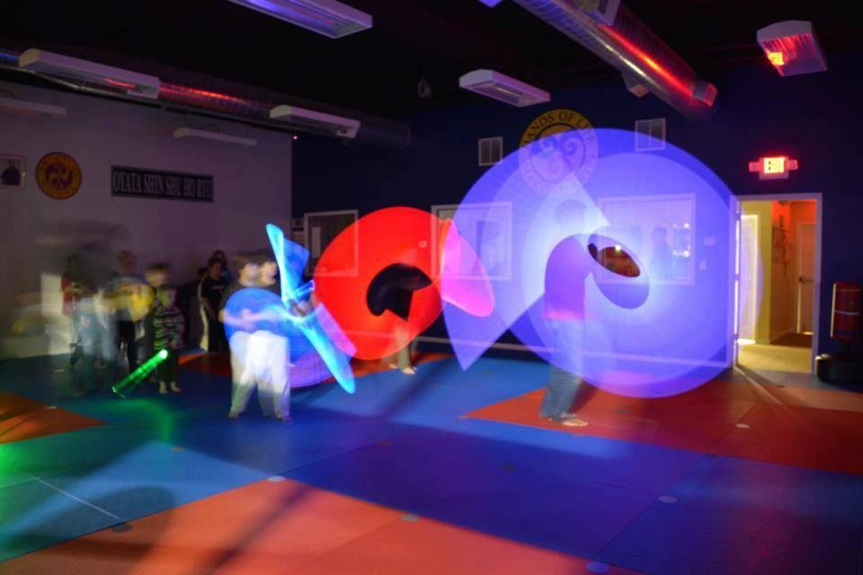 A group of people are playing with lightsabers in a dark room