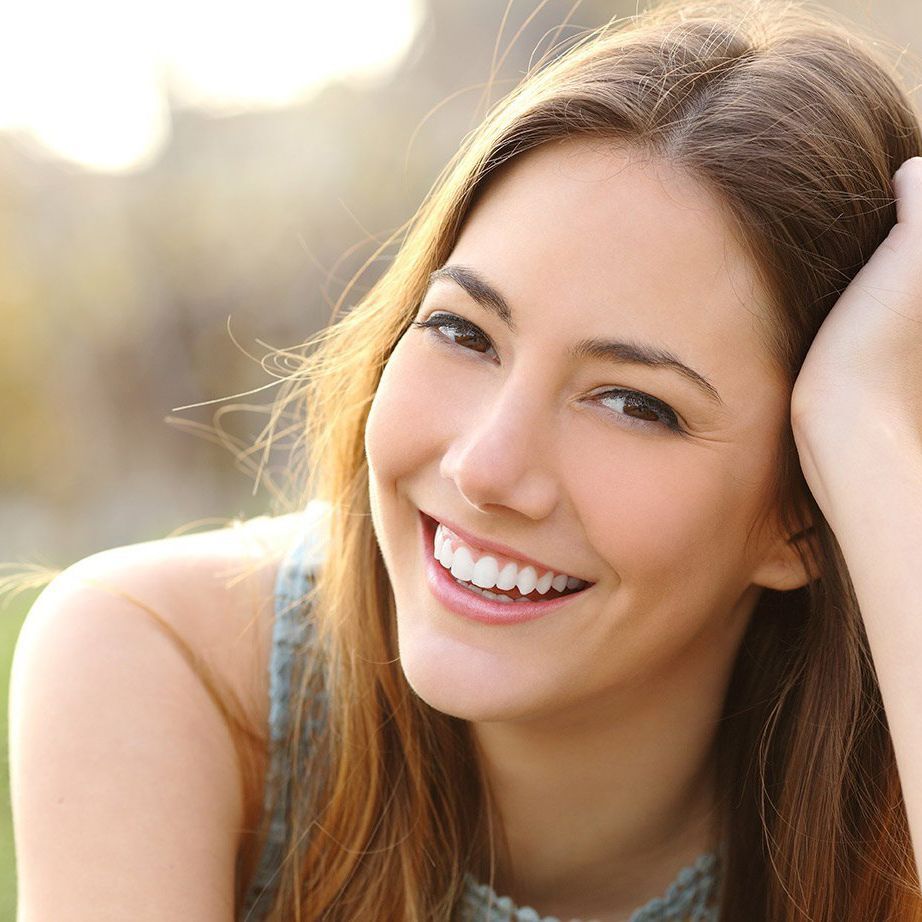 A woman is smiling with her hand in her hair.