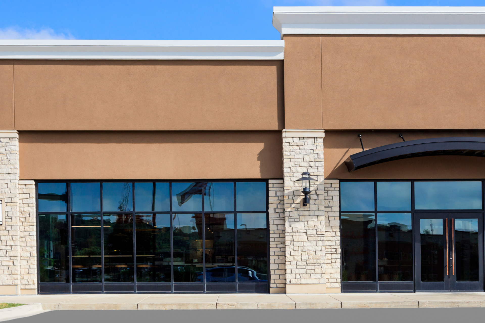 Storefront with brown walls, large windows, and stone columns.