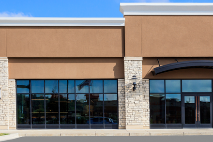 Storefront with brown walls, large windows, and stone columns.