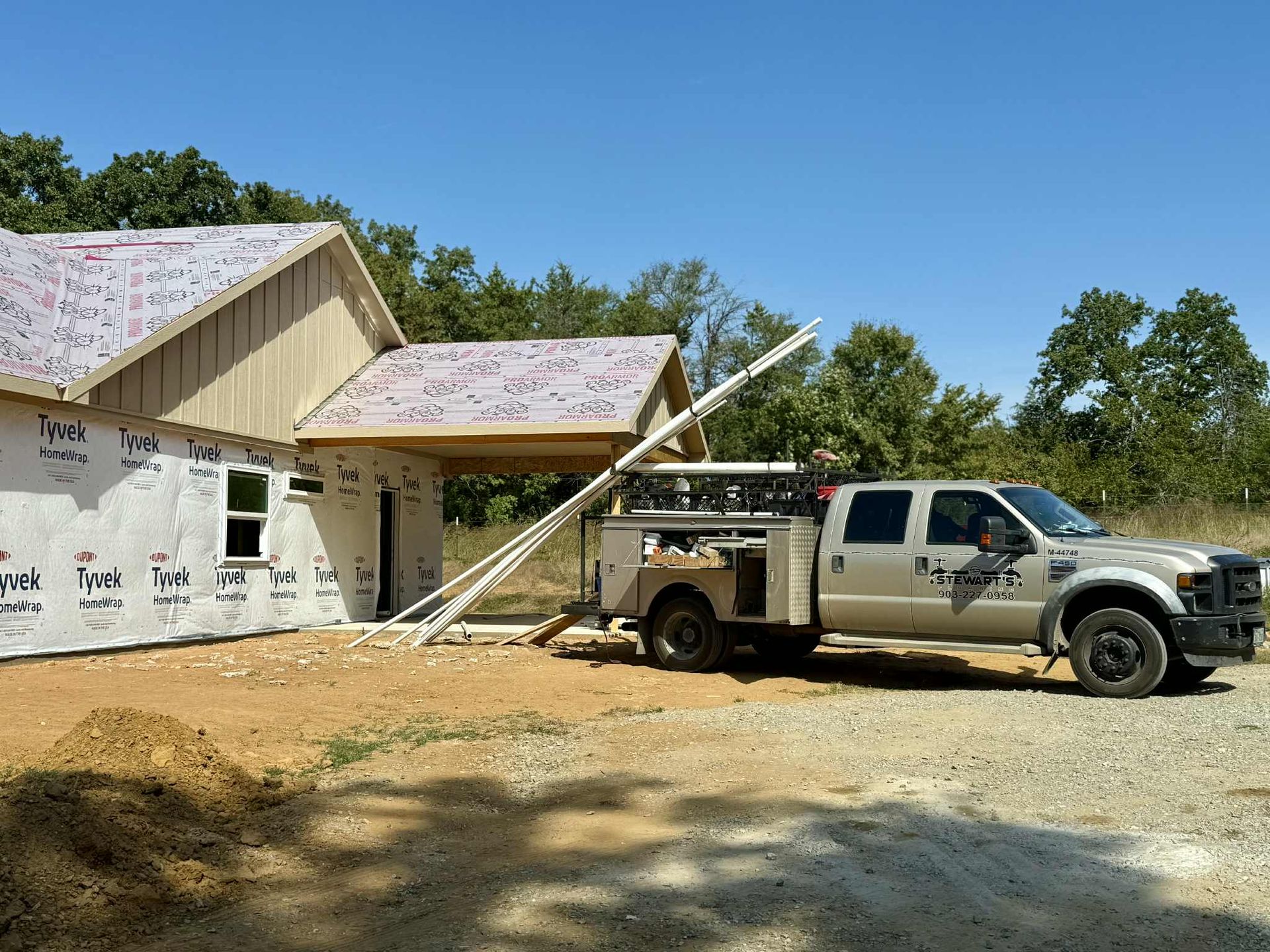 Construction site with a truck, partially built house, and materials on the ground.