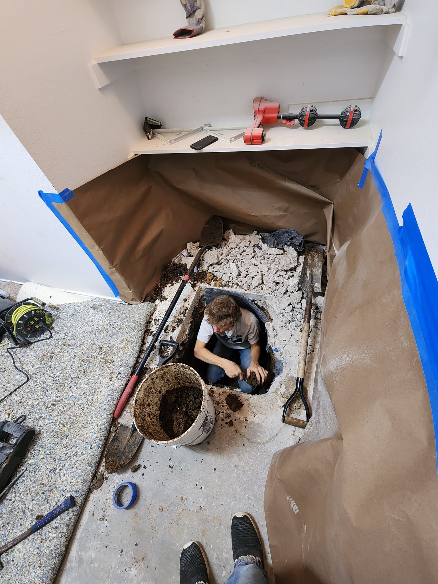 Person working inside a small hole in the floor.