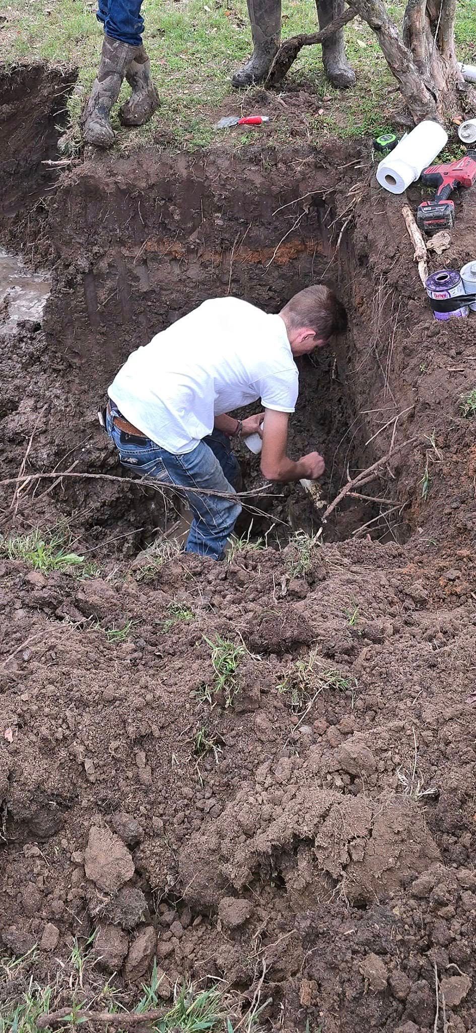 A person digging in a trench outdoors.