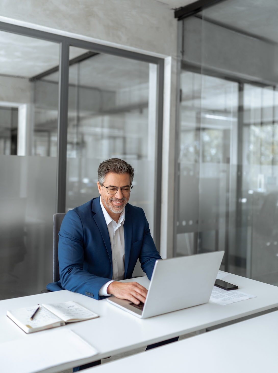 A man is sitting at a desk using a laptop and a tablet.