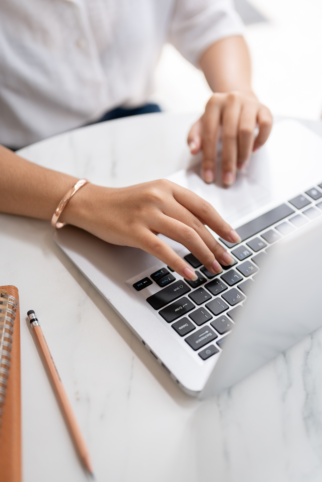 A man is sitting at a desk using a laptop and a tablet.