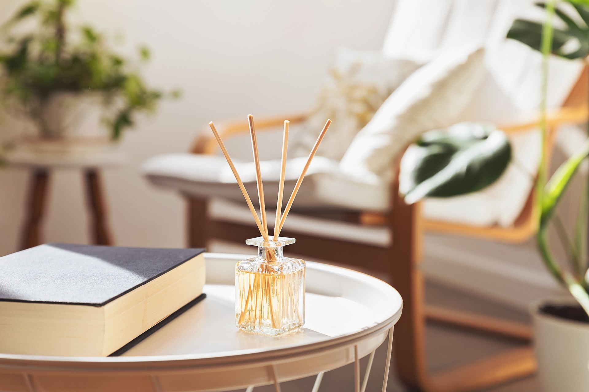 Un diffusore a bastoncini è appoggiato su un tavolo accanto a un libro.