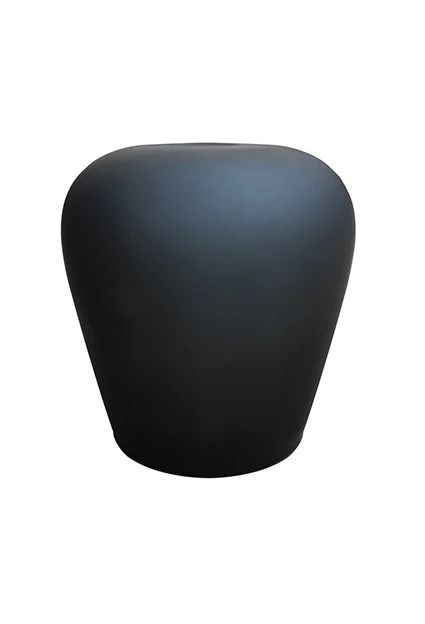 Un vaso nero è appoggiato su una superficie bianca.