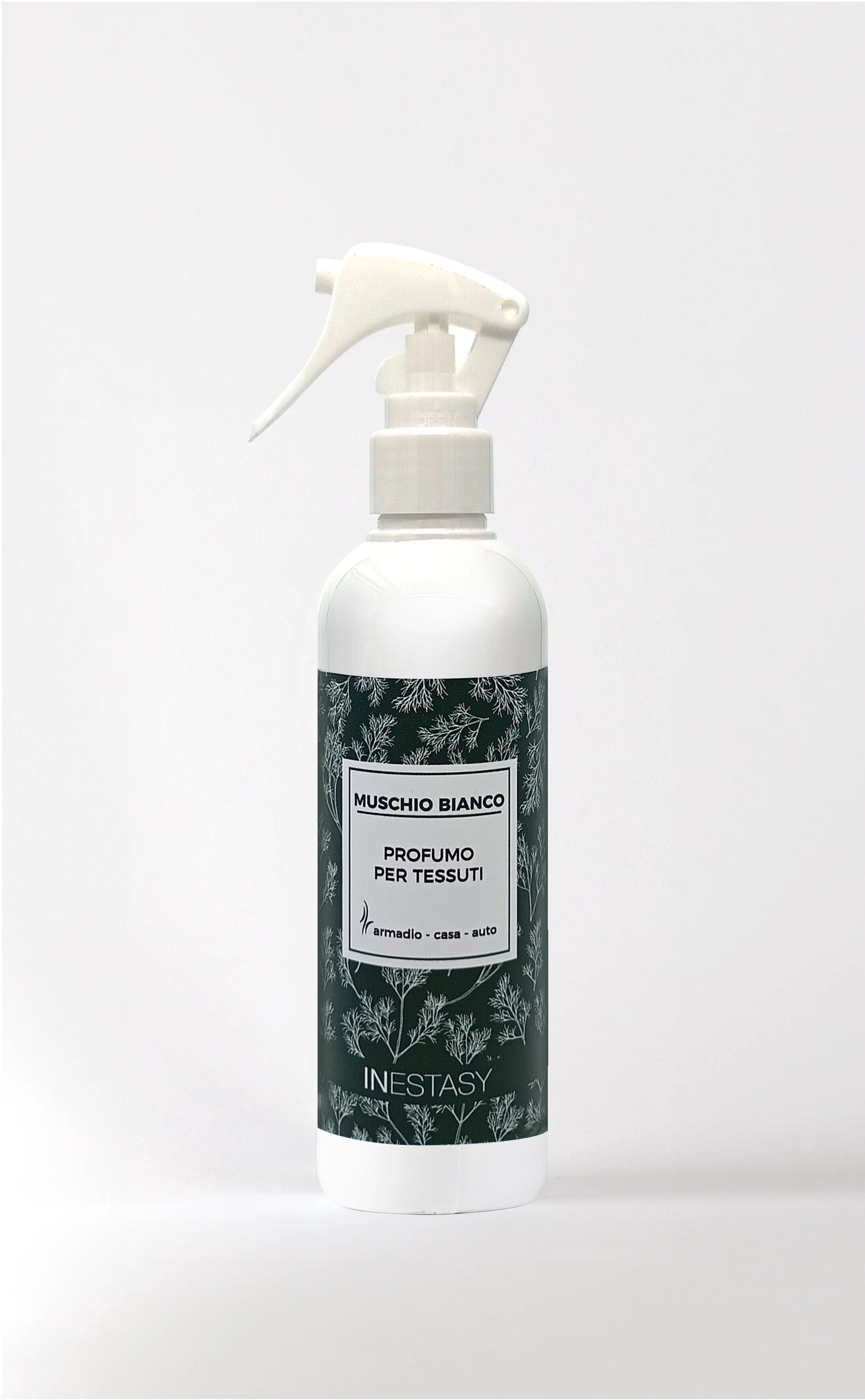 Una bottiglia spray bianca con un'etichetta verde è appoggiata su una superficie bianca.