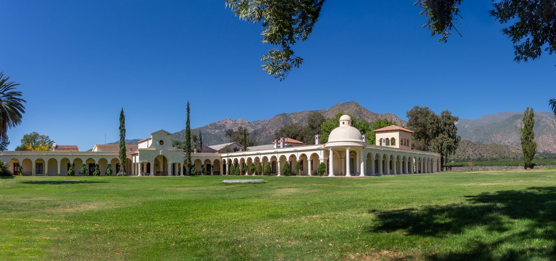 A large white building is sitting in the middle of a lush green field.