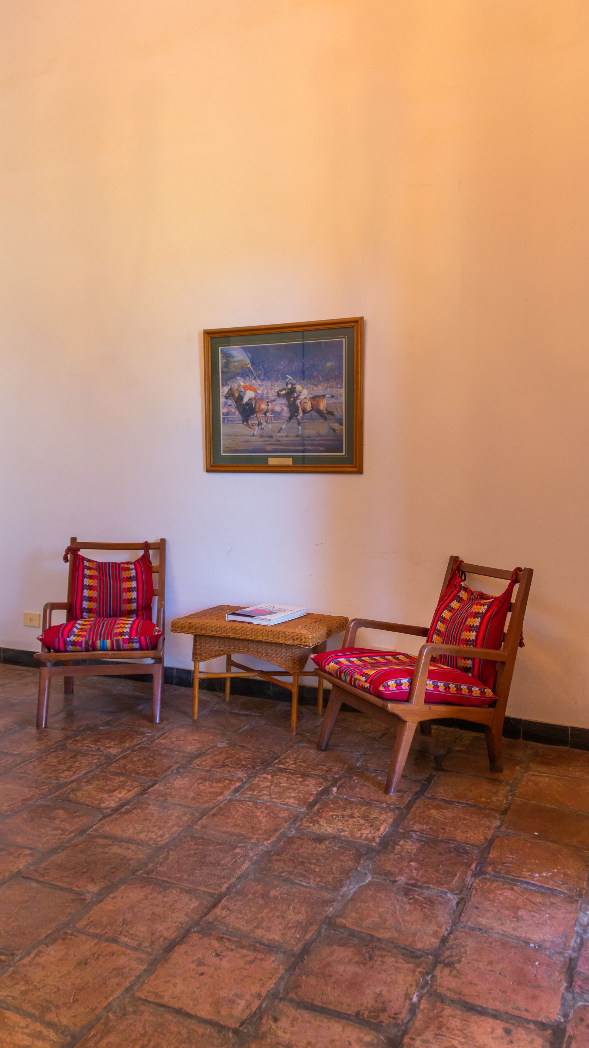 Two chairs and a table in a room with a painting on the wall.