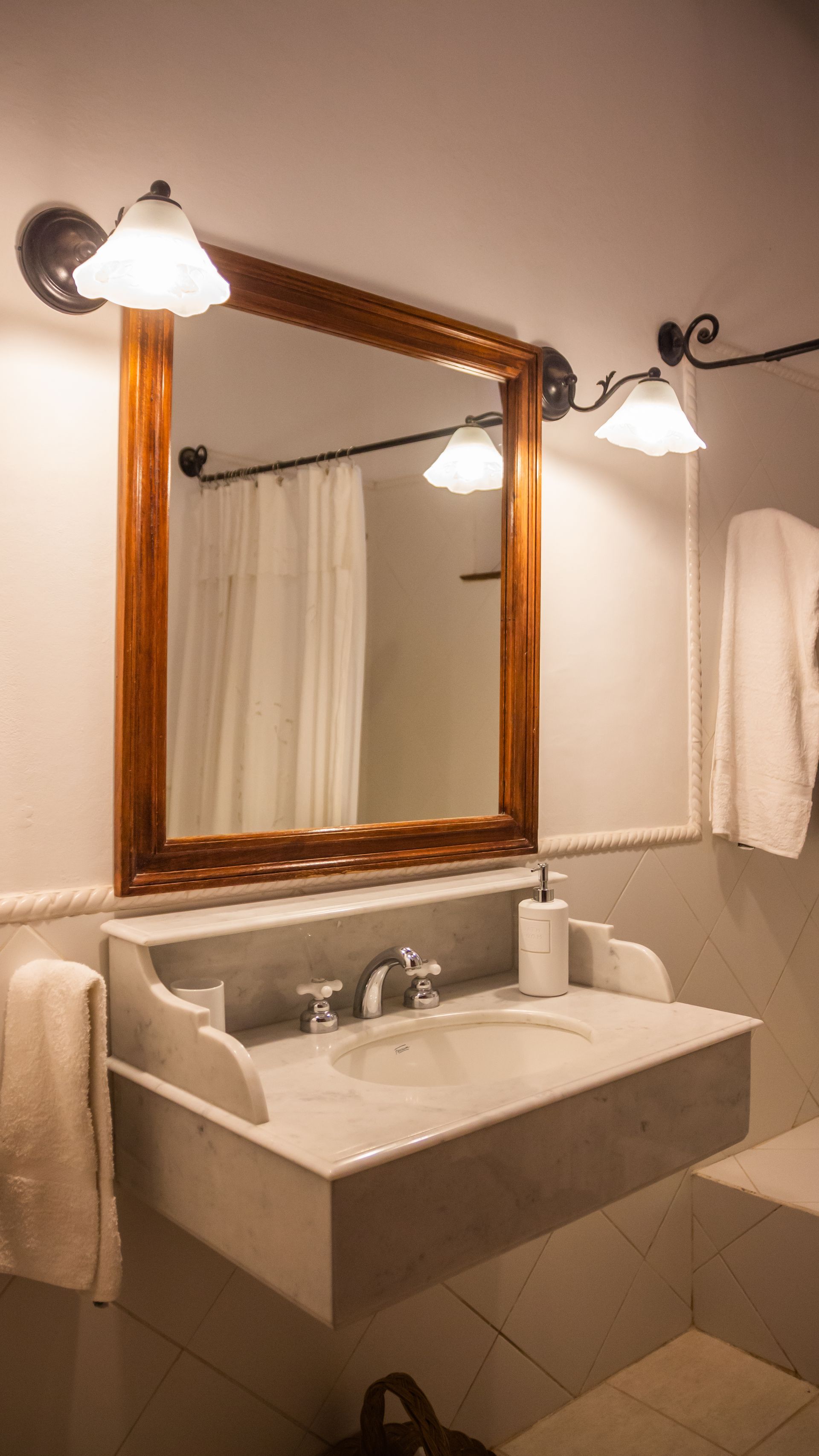 A bathroom with a sink , mirror and towels.