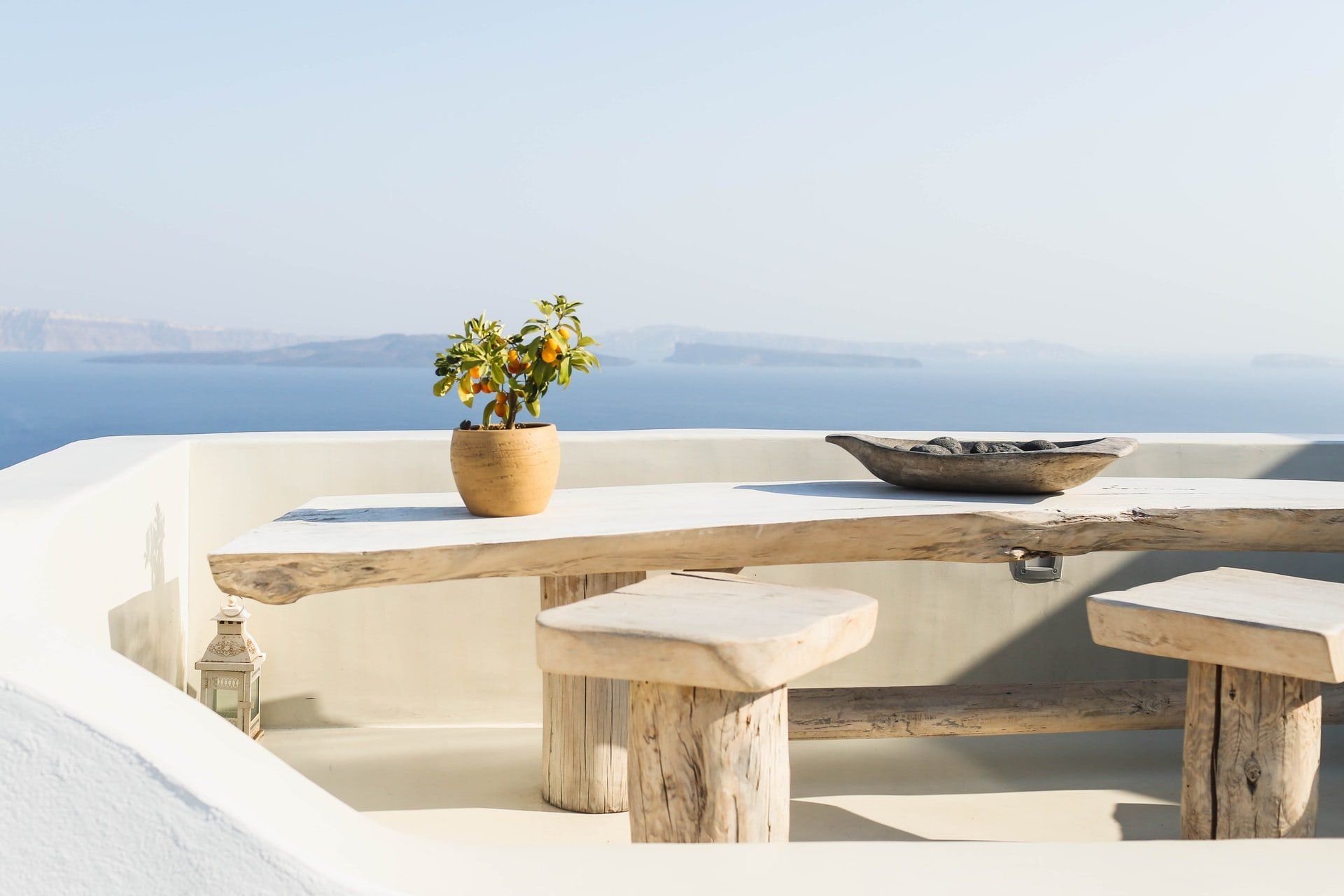 A wooden table and benches on a balcony overlooking the ocean.