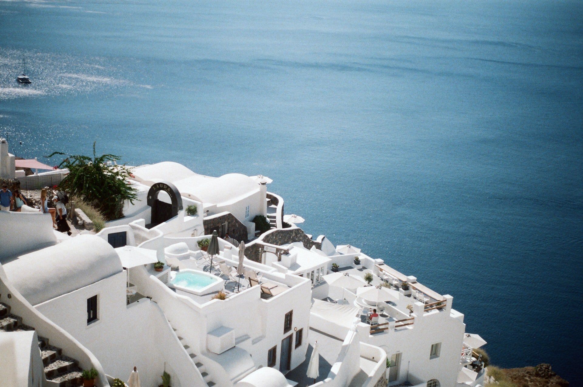 A white building on a hill overlooking a body of water.