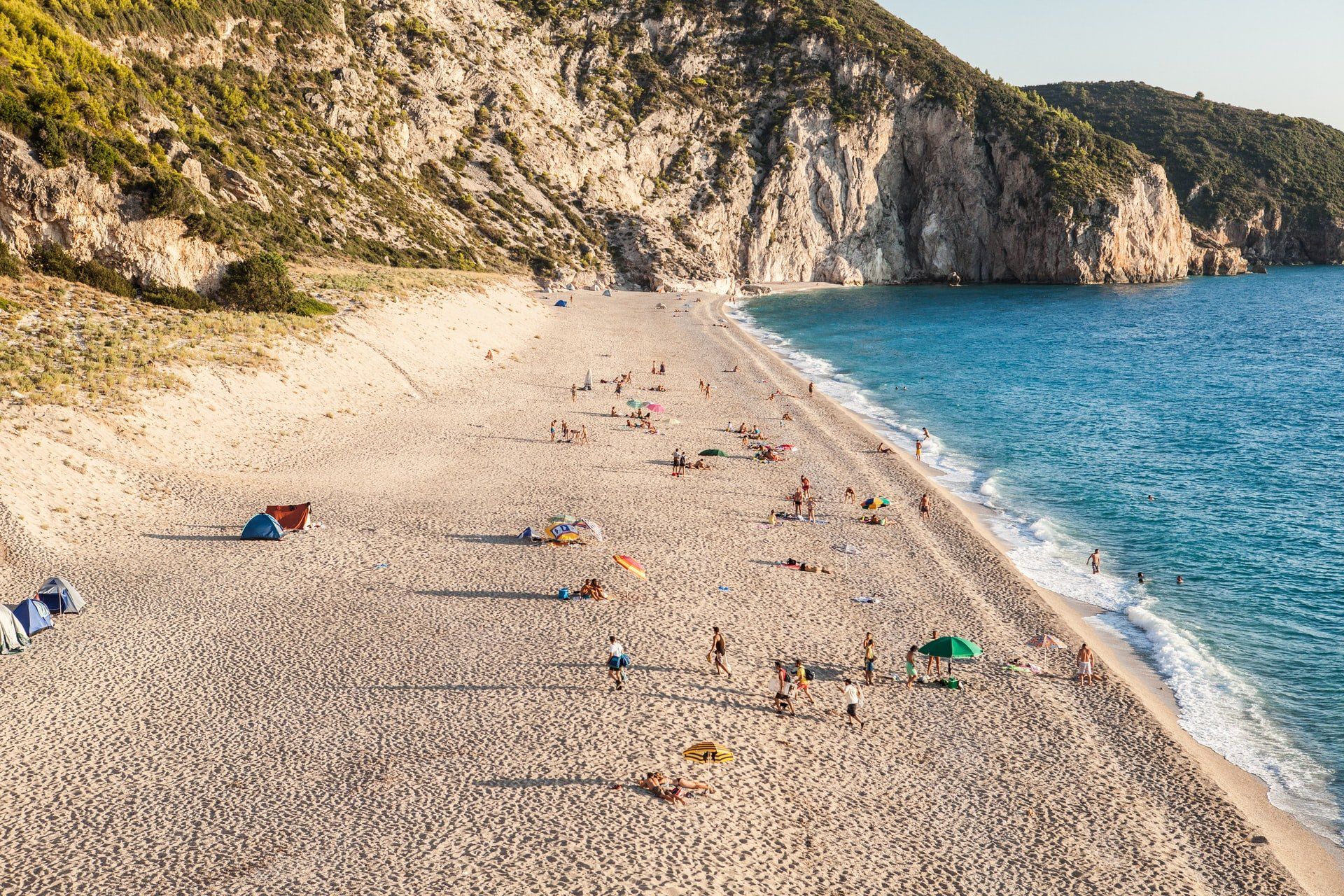 A group of people are sitting on a sandy beach near the ocean.