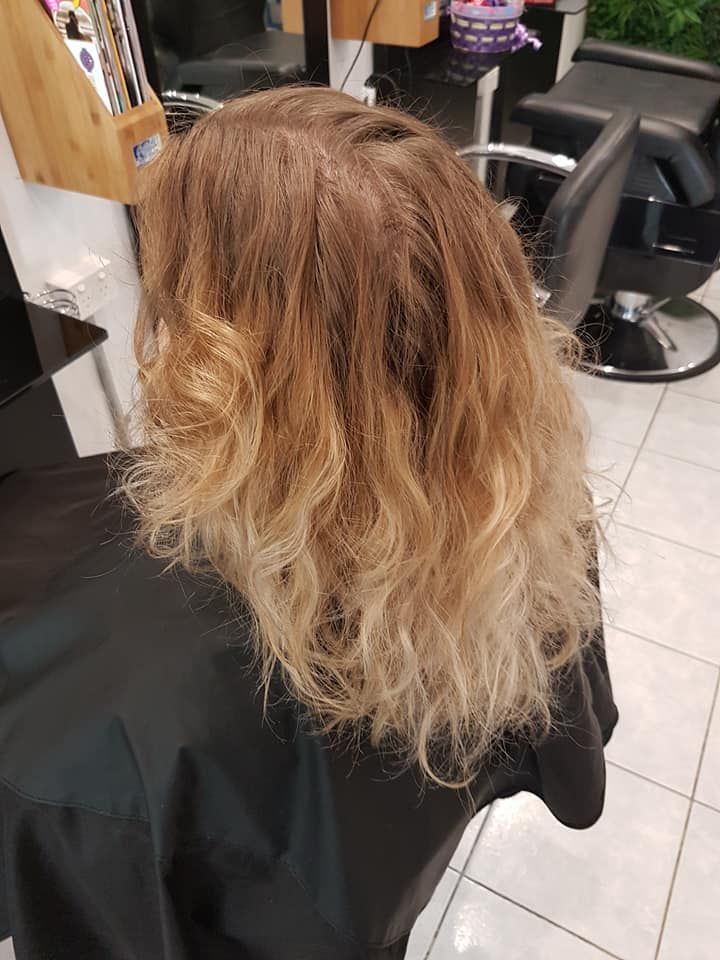 Woman With Light Brown to Blonde Ombre Hair in a Salon, Wearing a Black Cape — ClaireAbella Hair Studio In Kariong, NSW