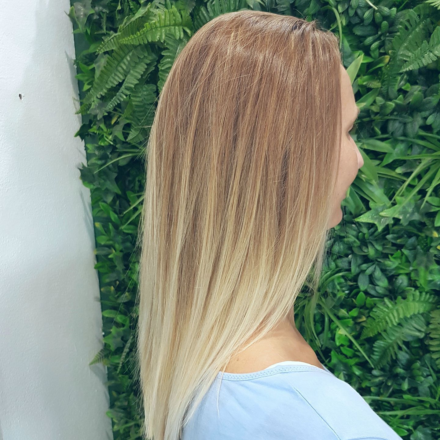 Woman With Long, Blonde Ombre Hair, Standing in Front of a Green Wall — ClaireAbella Hair Studio In Kariong, NSW