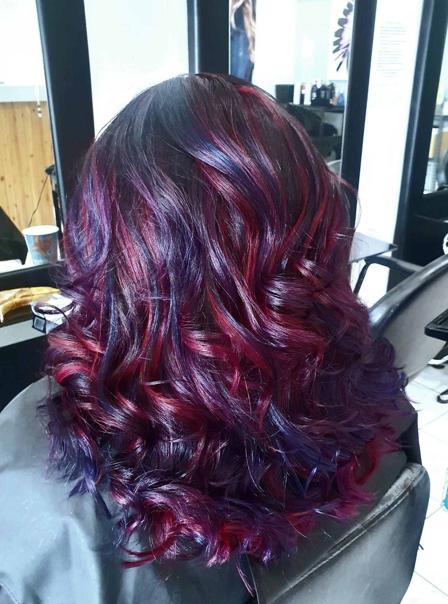 Woman's Hair Dyed With Vibrant Shades of Red and Purple, Styled in Loose Waves — ClaireAbella Hair Studio In Kariong, NSW