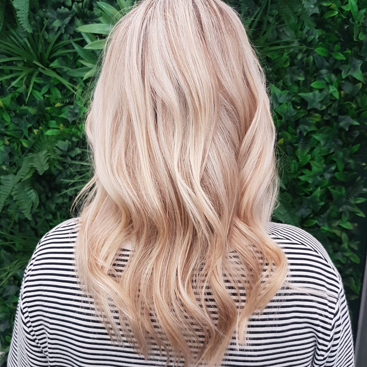 Blonde wavy hair against a green foliage background - ClaireAbella Hair Studio In Kariong, NSW