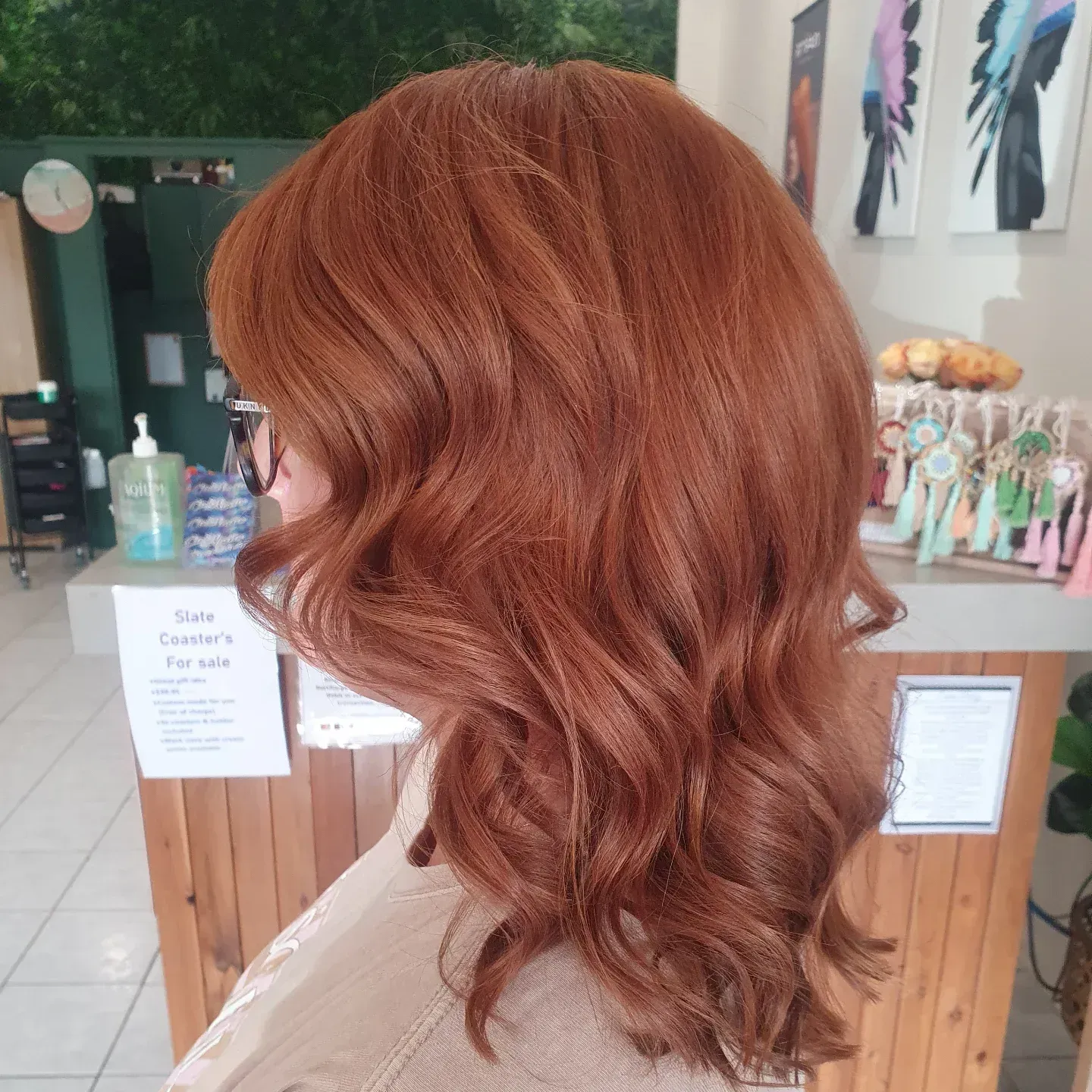 Woman With Wavy, Reddish-brown Hair Stands by a Wooden Counter in a Salon — ClaireAbella Hair Studio In Kariong, NSW